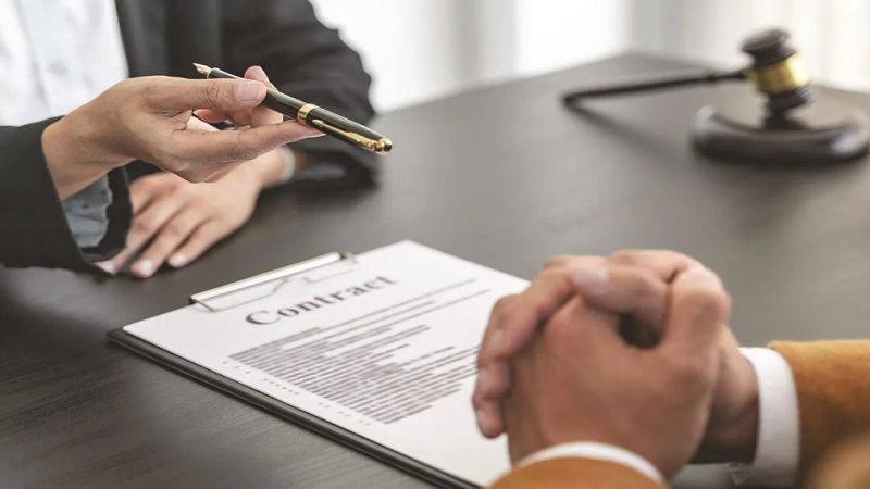 تصویر وکیلی که قولنامه ای صحیح با رعایت نکات حقوقی تنظیم کرده و موکل قصد امضا کردن ان را دارد.