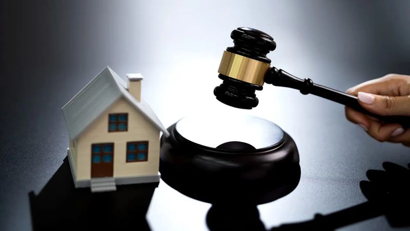 تصویر ماکت یک خانه که در کنار آن قاضی با چکش عدالت ضربه میزند و نمادی از صدور حکم است 