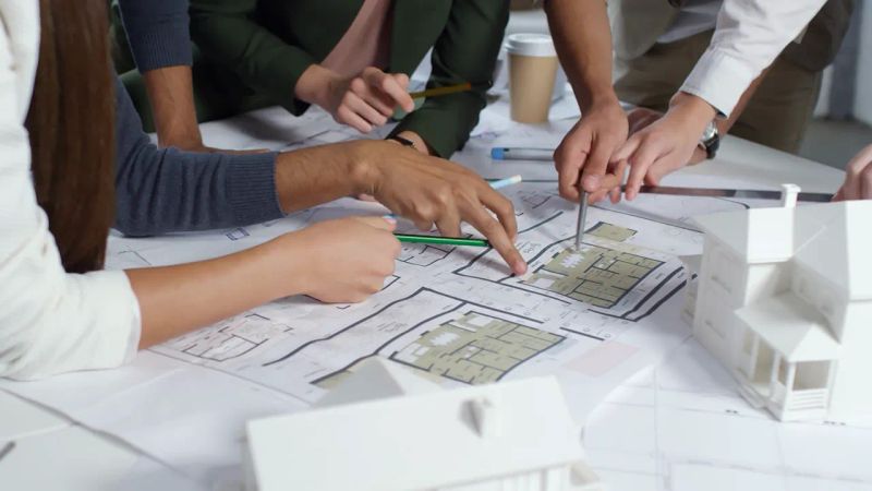 گروهی از اعضای شرکت معماری در حال کار کردن روی یک پروژه معماری